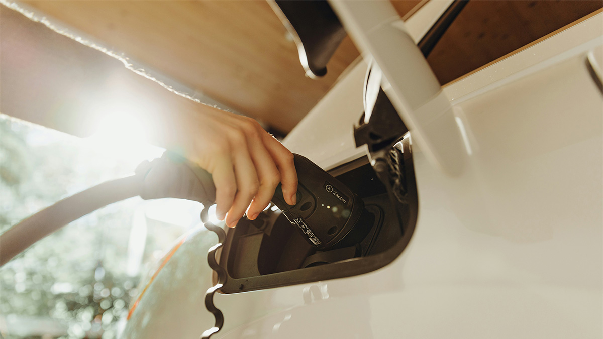 Hand plugging in charger into electric vehicle